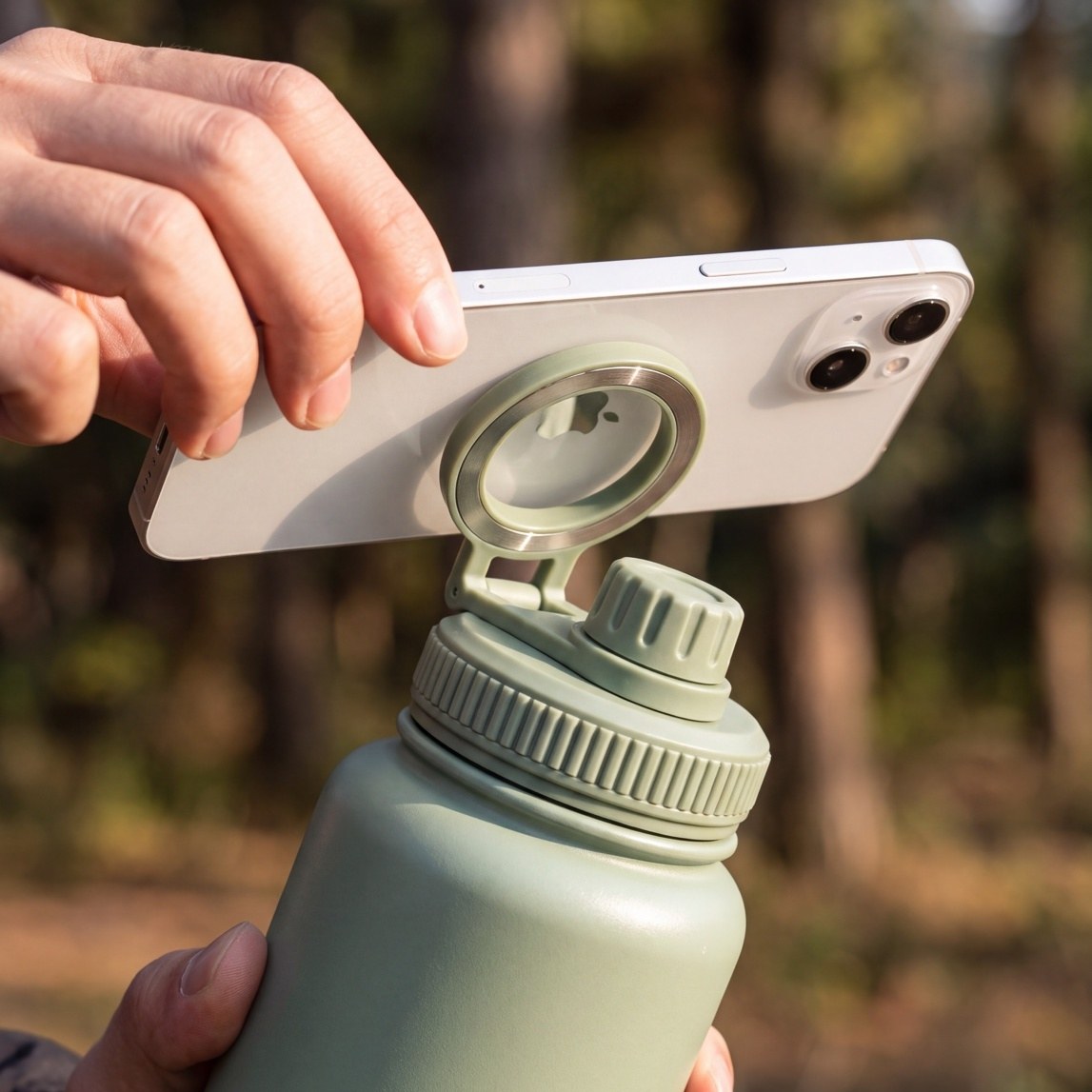 Un smartphone maintenu par le support magnétique de la gourde 3-en-1 LUMAYA lors d'une sortie en forêt